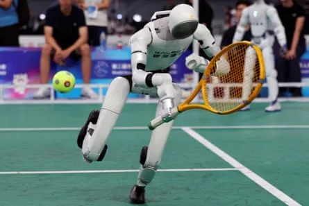 A robot holding a tennis racket dives for the ball.
